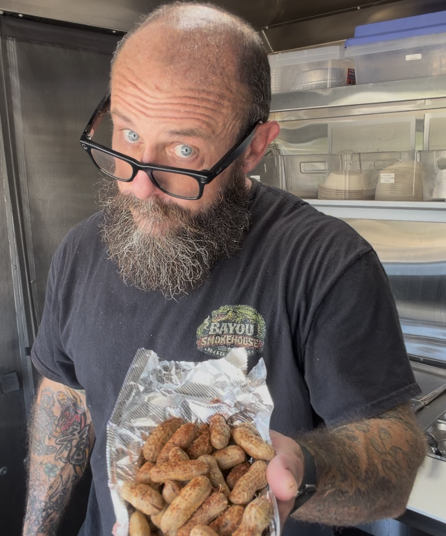 Chef Johnny at the Bayou Smokehouse truck, holding a bag of boiled peanuts